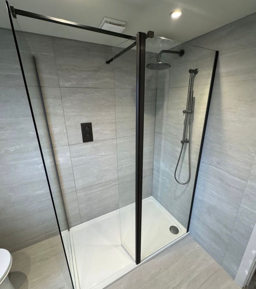 Black-framed walk-in shower enclosure with grey stone tiles